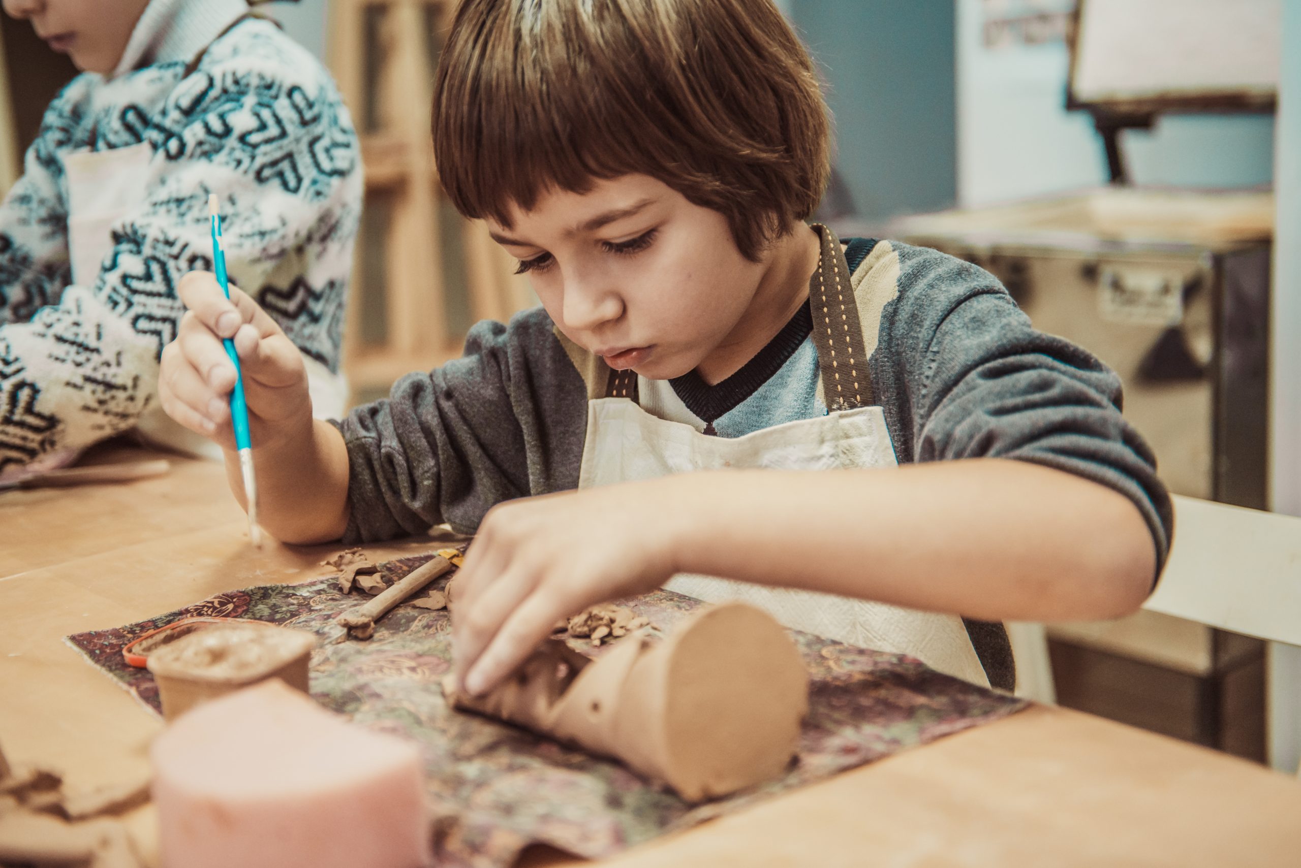 The child is engaged in a pottery school, sculpts a clay product